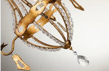 Load image into Gallery viewer, This exquisite petite chandelier features stunning hand-beaded details, candleabra bulbs, and an antique gold finish. With a dimmable light and graceful design, it is topped off with a regal touch, evocative of a crown. It's perfect for adding elegance to any room, with ornate hand-beaded accents and a shimmering antique gold finish. Enjoy the soft, adjustable lighting while appreciating the refined design.