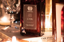 Load image into Gallery viewer, Experience the warm blend of indulgent cognac, aged leather, and rugged tobacco. Notes of delicate rose intertwine with smooth vanilla and distilled rum for an alluring essence. Inspired by the strength of rivets that bridge the gap between land, air, and sea, we present the Cask collection fuses design and destination.
