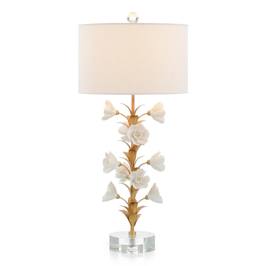 This table lamp showcases intricate white porcelain flowers, each with a brass petal, resting on a stunning crystal base.