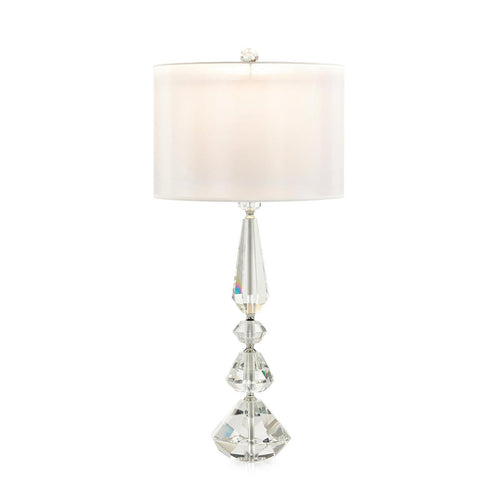 Crafted by expert hands, the Bailey crystal table lamp is a magnificent work of art. Made from clear crystal, this lamp flaunts an exquisitely carved pillar adorned with faceted shapes, complemented by a faceted ball finial. The polished nickel finish on the metal hardware creates a striking contrast against the crystal's pristine clarity, adding a touch of cool metallic tones to the overall design.