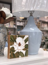 Load image into Gallery viewer, The Shelby lamp&#39;s sleek ceramic body is finished in a calming baby blue hue, perfect for any space that needs a pop of color while remaining congruous. Features a white linen shade and a sturdy gold base.
