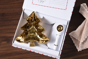 This Christmas Tree Serving Set is perfect for gifting or even as a personal treat to yourself. Packaged in a stylish magnetic closure gift box, the inside cover features a customizable sentiment. With a festive tree-shaped bowl and a white porcelain spoon with gold accents, this set is ideal for serving candies, nuts, fruit, or condiments. Made from stunning gold-tone titanium-finished porcelain, this set adds a touch of elegance to any table setting.