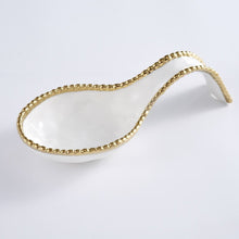 Load image into Gallery viewer, Effortlessly stylish and functional, the Golden Beaded Spoon Rest is a must-have for any dinner party. Keep your serving utensils neat and tidy while impressing your guests with this stunning and practical accessory. Perfect for buffets and maintaining a clean kitchen, this spoon rest is an essential addition to your table setting. Made of high-quality white porcelain with shimmering gold beads made of titanium.
