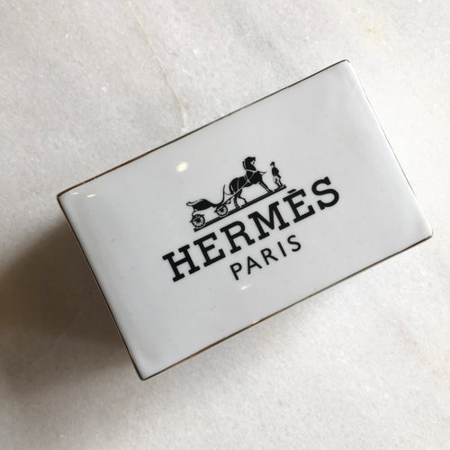 Impress your connections with this ceramic notecard box adorned with a chic fashion insignia. Accompanied by a set of matching notecards, this set is the epitome of tasteful luxury and elegance. It's the perfect way to leave a lasting impression with your personal touch.