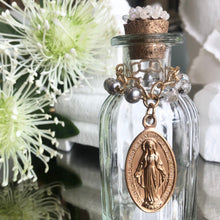 Load image into Gallery viewer, Holy Water Bottle adorned with vintage hand painted miraculous Mary medallion. Golden cork topper with embossed vintage metal, accoutrements and tops vary. Each bottle is unique, and as such, may not be precisely as depicted. We invite you to celebrate the differences on this handmade product.
