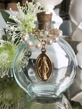 Load image into Gallery viewer, Holy Water Bottle adorned with vintage hand painted miraculous Mary medallion. Golden cork topper with embossed vintage metal, accoutrements and tops vary. Each bottle is unique, and as such, may not be precisely as depicted. We invite you to celebrate the differences on this handmade product.
