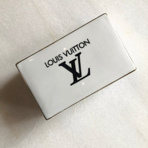 Impress your connections with this ceramic notecard box adorned with a chic fashion insignia. Accompanied by a set of matching notecards, this set is the epitome of tasteful luxury and elegance. It's the perfect way to leave a lasting impression with your personal touch.