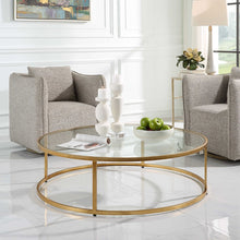 Load image into Gallery viewer, The Radius Coffee Table is an ideal addition to contemporary settings, showcasing a durable iron frame with a subtle antique gold finish. Its sleek, clear glass tabletop adds a touch of elegance to any room.
