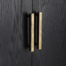 Load image into Gallery viewer, Perfect for any space with its sleek design and timeless finishes. The dark ebony oak veneer is accented by aged gold linear iron pulls. Includes one fixed shelf inside.
