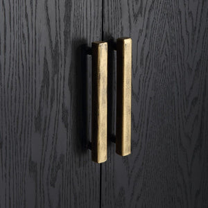 Perfect for any space with its sleek design and timeless finishes. The dark ebony oak veneer is accented by aged gold linear iron pulls. Includes one fixed shelf inside.