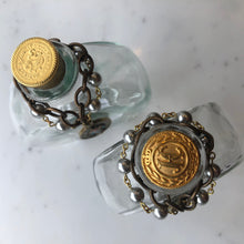 Load image into Gallery viewer, Holy Water Bottle adorned with vintage hand painted miraculous Mary medallion. Golden cork topper with embossed vintage metal, accoutrements and tops vary. Each bottle is unique, and as such, may not be precisely as depicted. We invite you to celebrate the differences on this handmade product.
