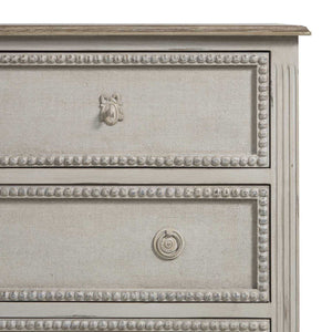 French-style 18th century inspired chest with beaded burlap drawer fronts and carved legs, with an antiqued white finish